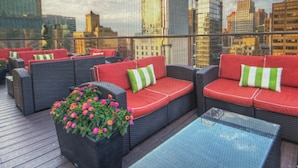 A rooftop lounge with red and black wicker furniture, green and white striped cushions, and a flower planter. - Cozy 1-bedroom condo with AC in peaceful New York.  For World Cup Soccer!! (New York)