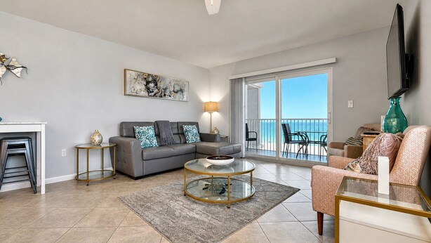 Ein geräumiges Wohnzimmer mit einer Couch, einem Couchtisch und einem Balkon mit Blick.