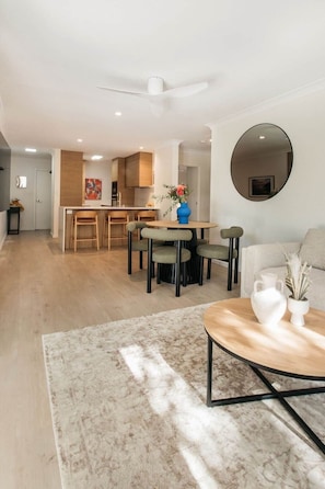 A modern living room with a round coffee table, a sofa, and a dining area with chairs. - Clarkes Beach Elevated. Water front. Ocean views from cozy sun drenched balcony. (Byron Bay)