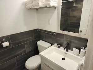 Une salle de bain moderne équipée de toilettes, d’un lavabo et d’un porte-serviettes.