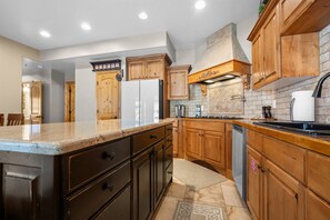 A kitchen with wooden cabinets, a granite countertop, a stainless steel sink, and a built-in oven. - Summit View at Cascade C106 |Hot Tub | Pool | Golf (Eden)