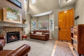 A living room with a fireplace, leather sofa, and a wooden door. - Summit View at Cascade C106 |Hot Tub | Pool | Golf (Eden)