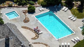 A large rectangular pool with a surrounding deck, lounge chairs, and a smaller adjacent pool.