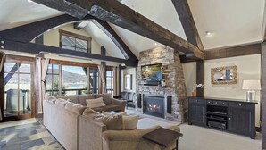 Una sala de estar con chimenea de piedra, un sofá grande y un televisor.