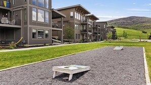 A multi-story building with balconies, a grassy area, and a playground. - Shred Reckoning | Pineview | Pool |  Hot Tub (Huntsville)
