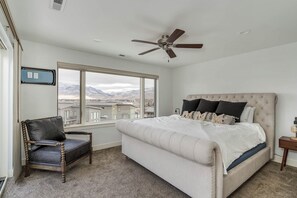 A bedroom with a bed, a chair, a ceiling fan, a window with a view, and a wall-mounted outlet. - Luvin Life EW21 | Hot Tub | Lake Views | Pool (Huntsville)