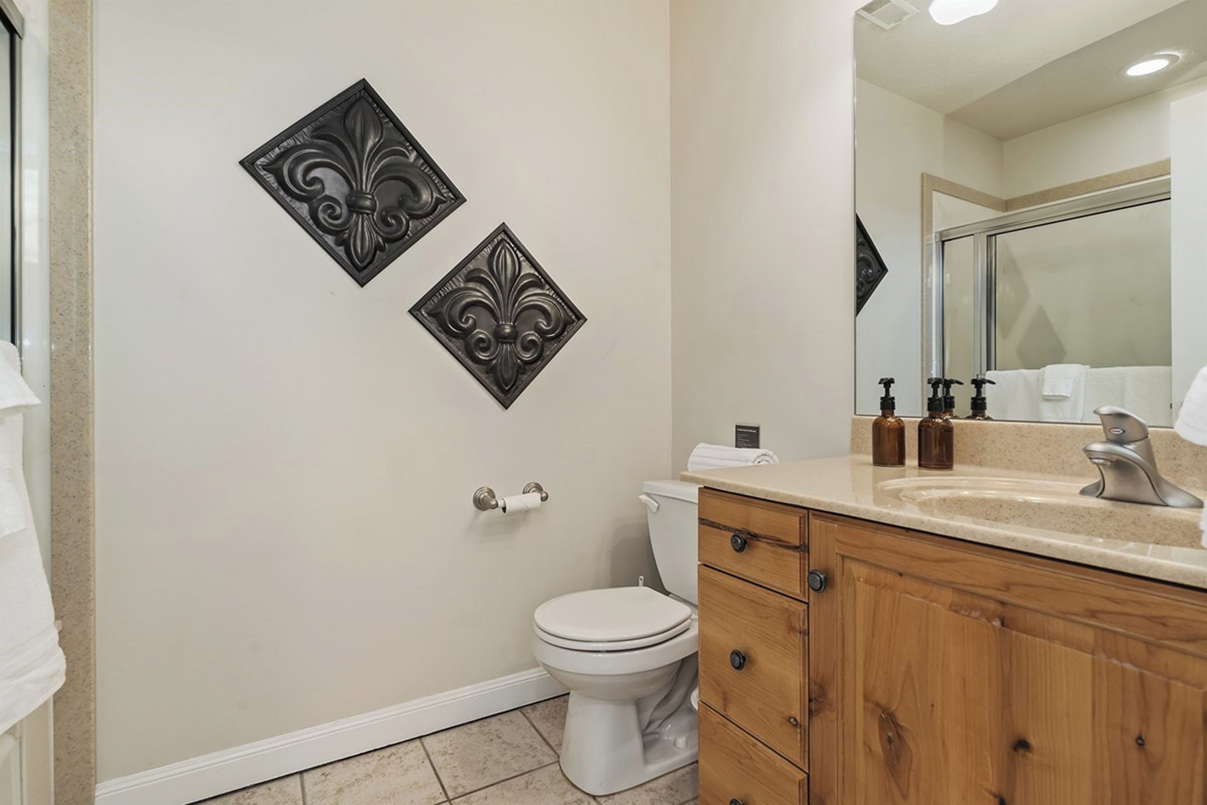 A bathroom with a toilet, a sink with a mirror, and decorative wall panels.