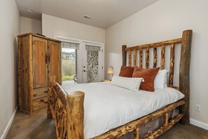 Quarto com estrutura de cama de madeira, guarda-roupa e parede de pedra.