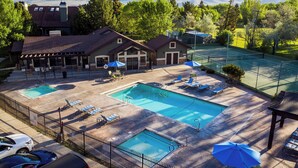 Un espace piscine comprenant deux piscines, des chaises longues, des parasols et une vue sur les montagnes.