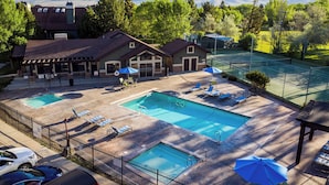 A pool area with two pools, lounge chairs, umbrellas, and a view of mountains. - Lakeside Getaway LS14A | Hot Tub | Dog-Friendly (Huntsville)