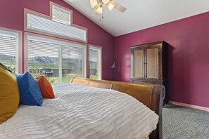 Une chambre à coucher avec un lit, des oreillers, une armoire en bois et une vue sur l’extérieur.