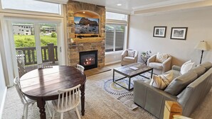 Una sala de estar con chimenea de piedra, televisor, mesa de comedor y sofá.