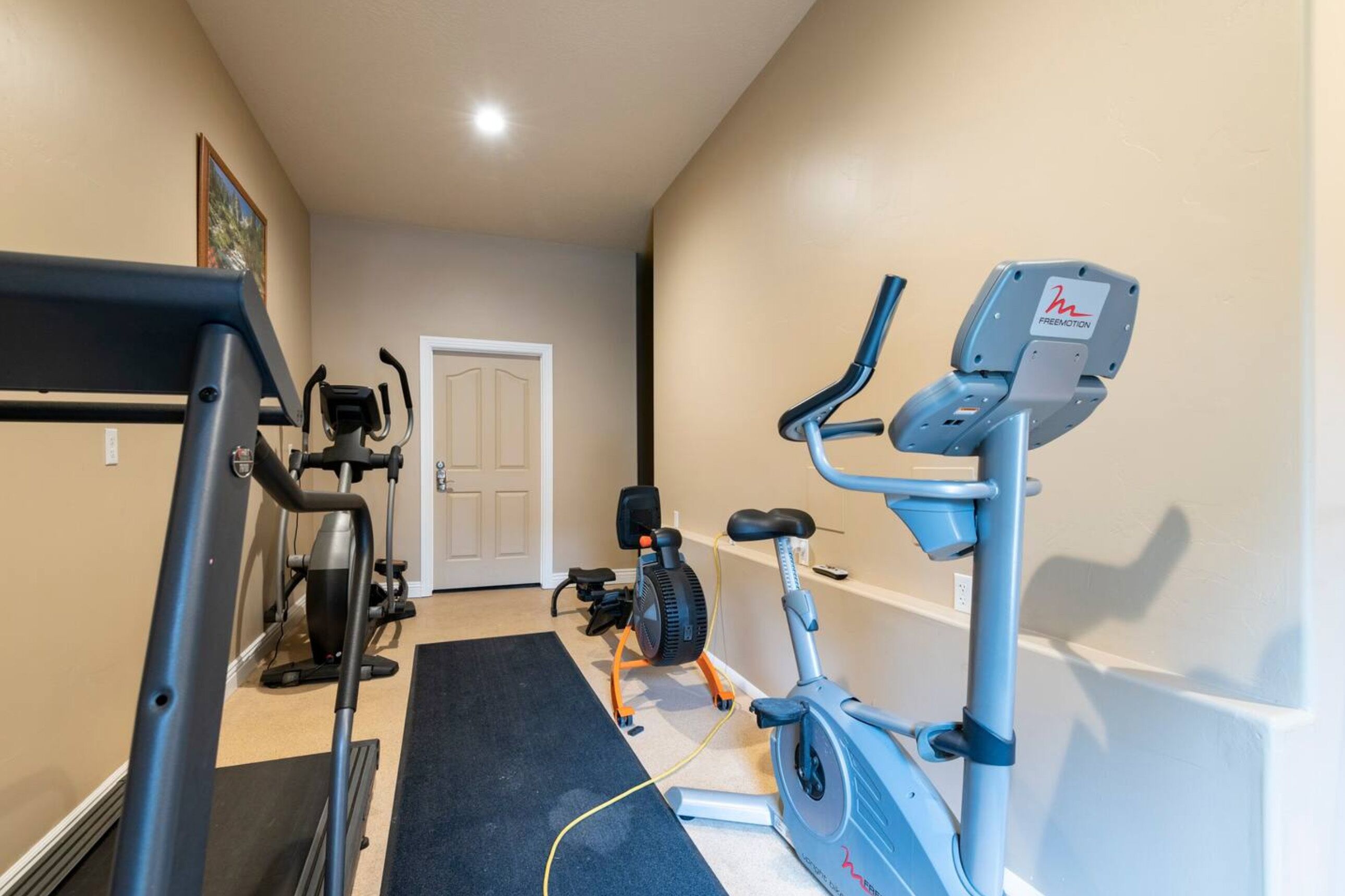 A home gym with a treadmill, elliptical, and stationary bike.