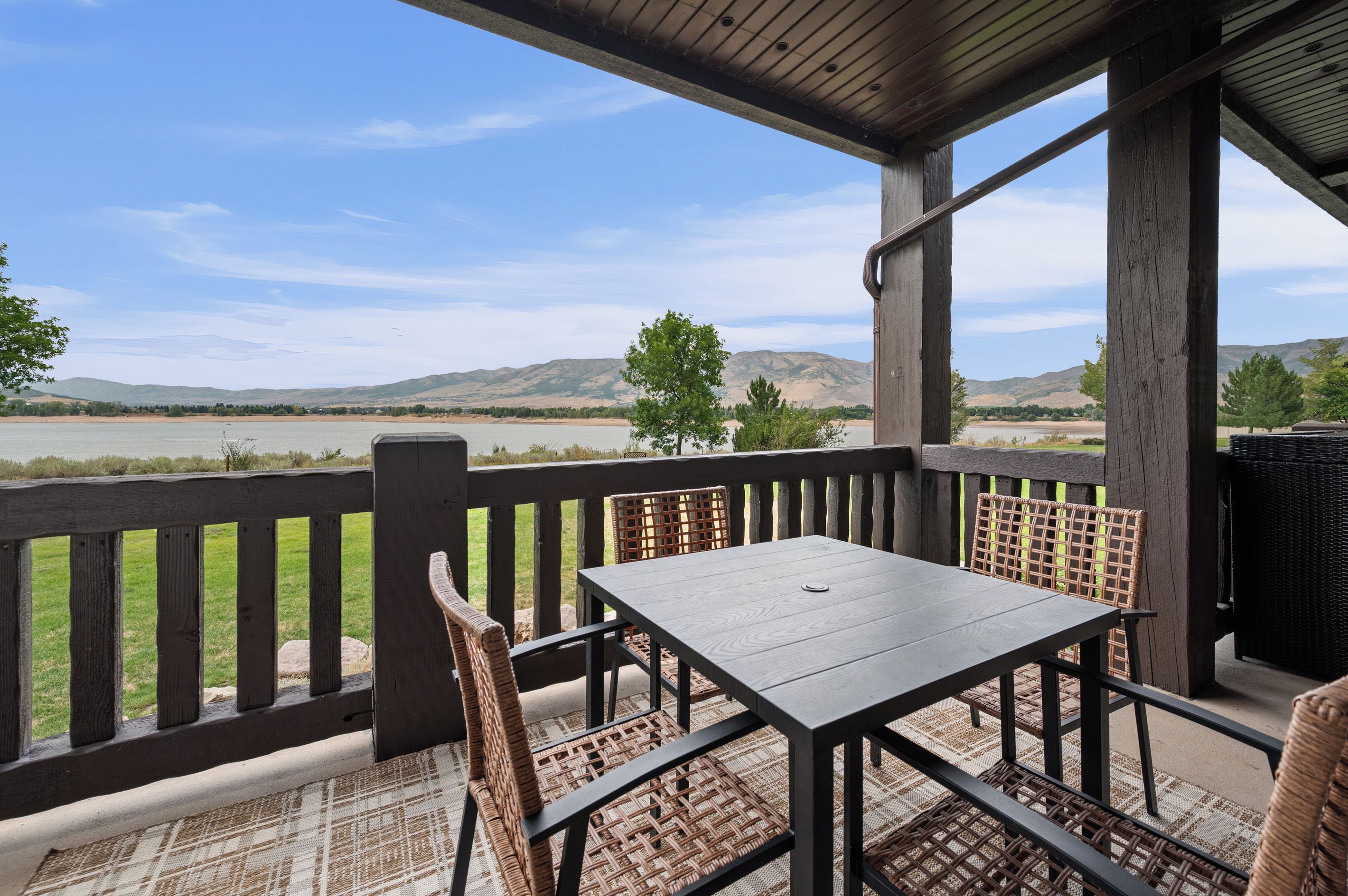 A covered outdoor seating area with a view of a lake and hills.