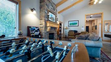 A cozy living room with a foosball table, a stone fireplace, and a comfortable sofa.