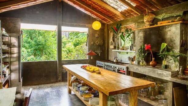 A rustic kitchen with a wooden table, a stove, and shelves with plants. - Vereda Yelapa: Passion Fruit (Yelapa)