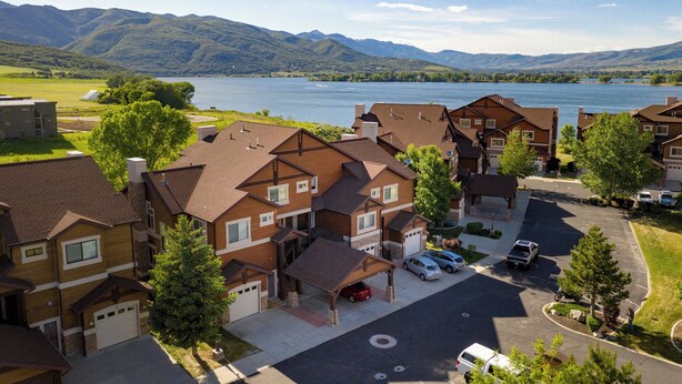 Un quartiere residenziale con case, un parcheggio e un lago con montagne sullo sfondo.