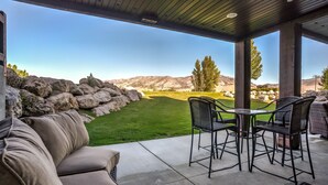 Una veranda coperta con vista su un giardino curato, un tavolo con sedie e un divano.