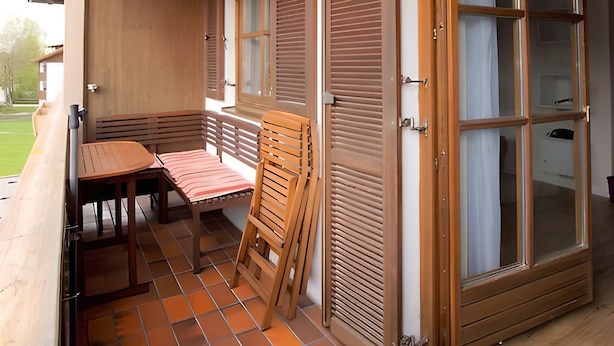 A balcony with a wooden table and chairs, a sliding door, and a view of the outdoors. - 4-Star Vacation Rental in Benediktenwand with Mountain Views and a Balcony (Lenggries)