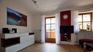 A modern living room with a TV, a painting, and a view of a bridge. - 4-Star Vacation Rental in Benediktenwand with Mountain Views and a Balcony (Lenggries)