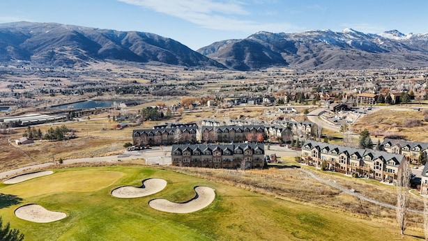 Ein Resort mit mehreren Gebäuden, einem Golfplatz und Bergen im Hintergrund.