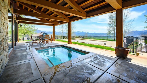 A covered outdoor pool area with a stone patio, wooden pergola, and a view of mountains. - Piney Mountain Escape TR5 | Hot Tub | Pool | Games (Eden)