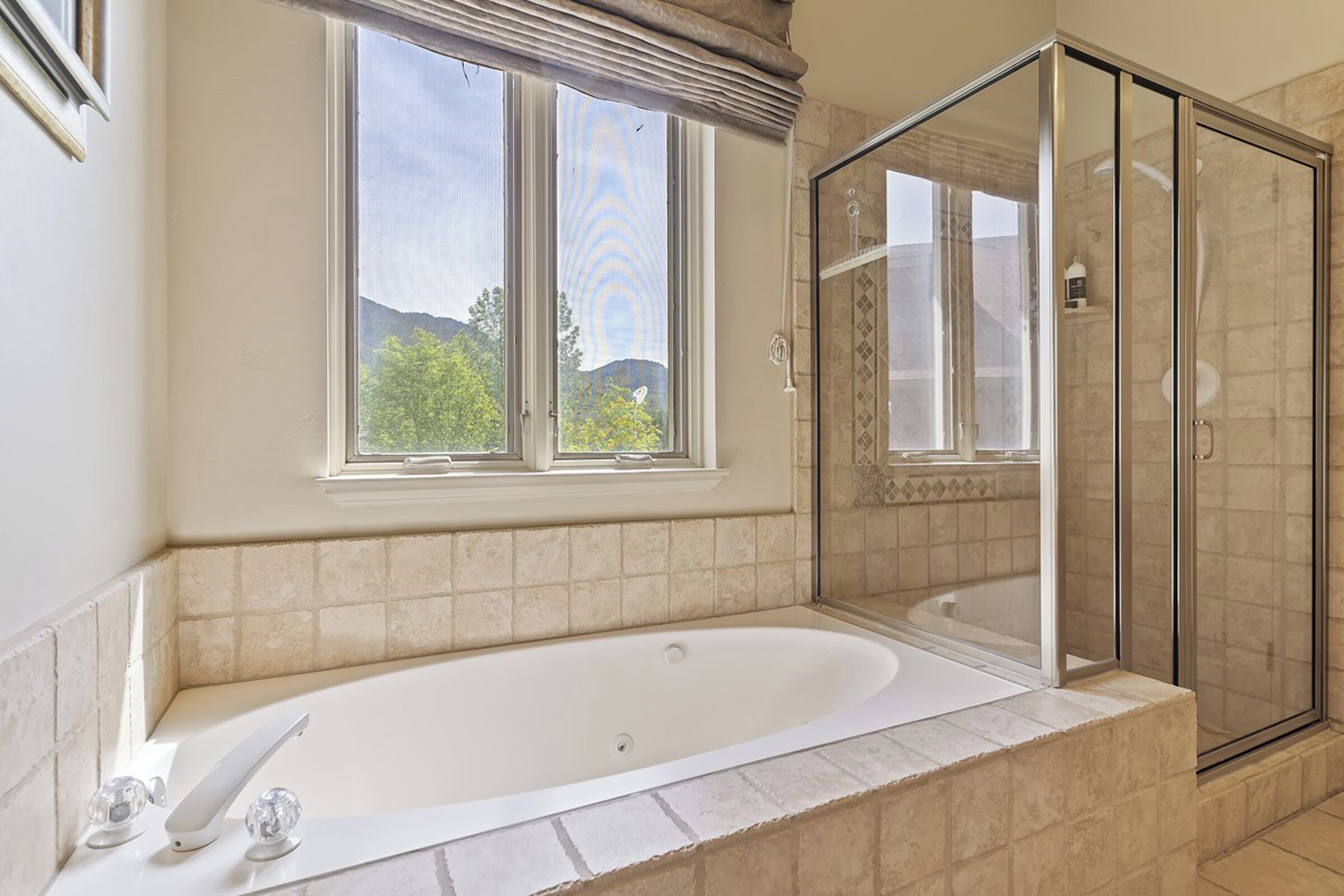 Une salle de bain avec une baignoire, une douche et une fenêtre.