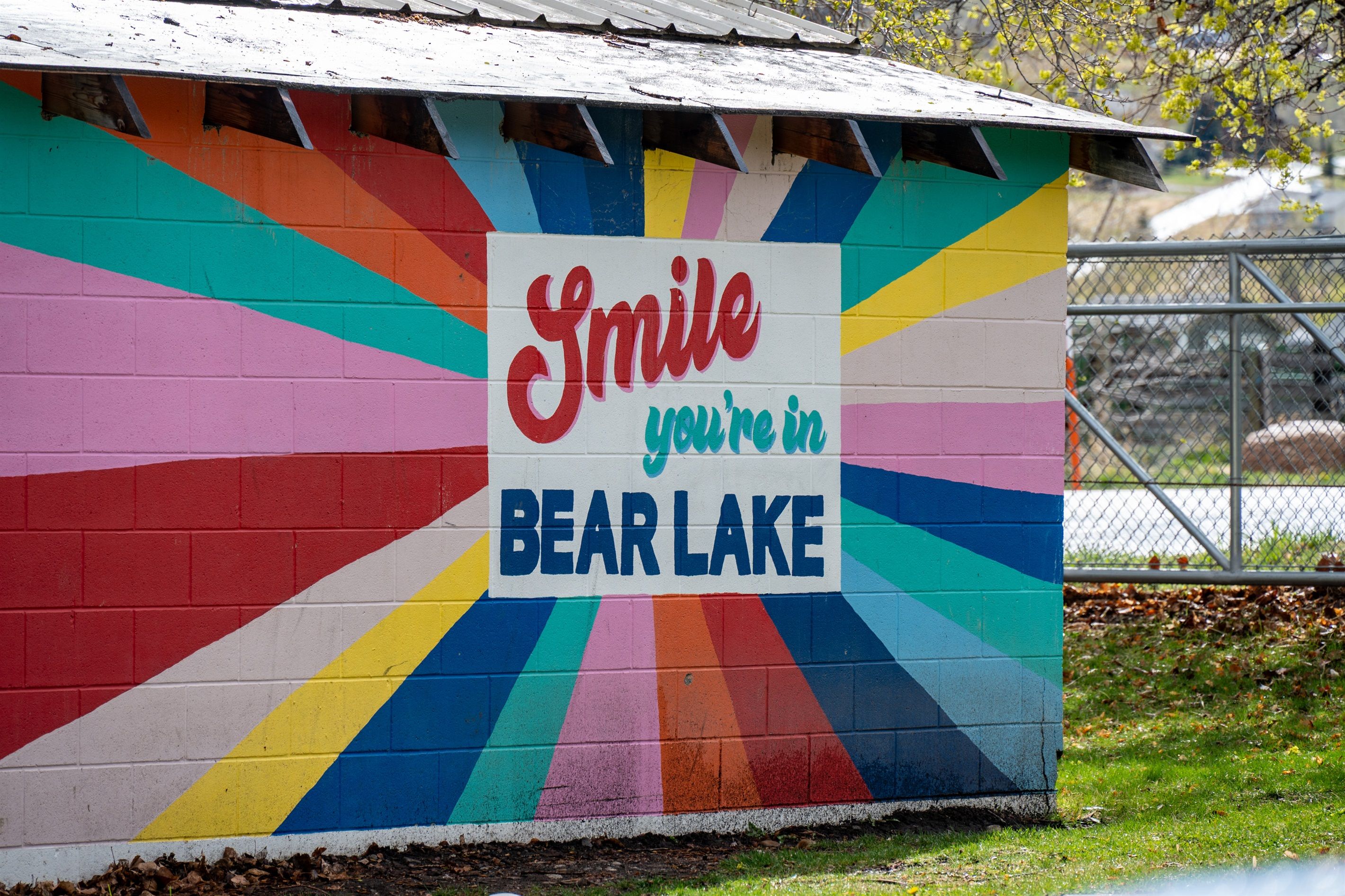 A colorful wall with a sign that reads 'Smile you're in BEAR LAKE.'