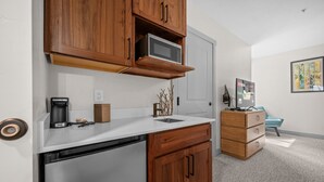 A compact kitchen with wooden cabinets, a microwave, a coffee maker, and a dishwasher. - Water's Edge 102C | Bear Lake| Lakeside Unit (Garden City)