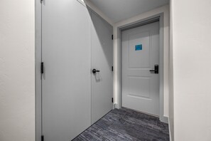 A hallway with a white door, a doorbell, and a carpeted floor. - Water's Edge 102C | Bear Lake| Lakeside Unit (Garden City)