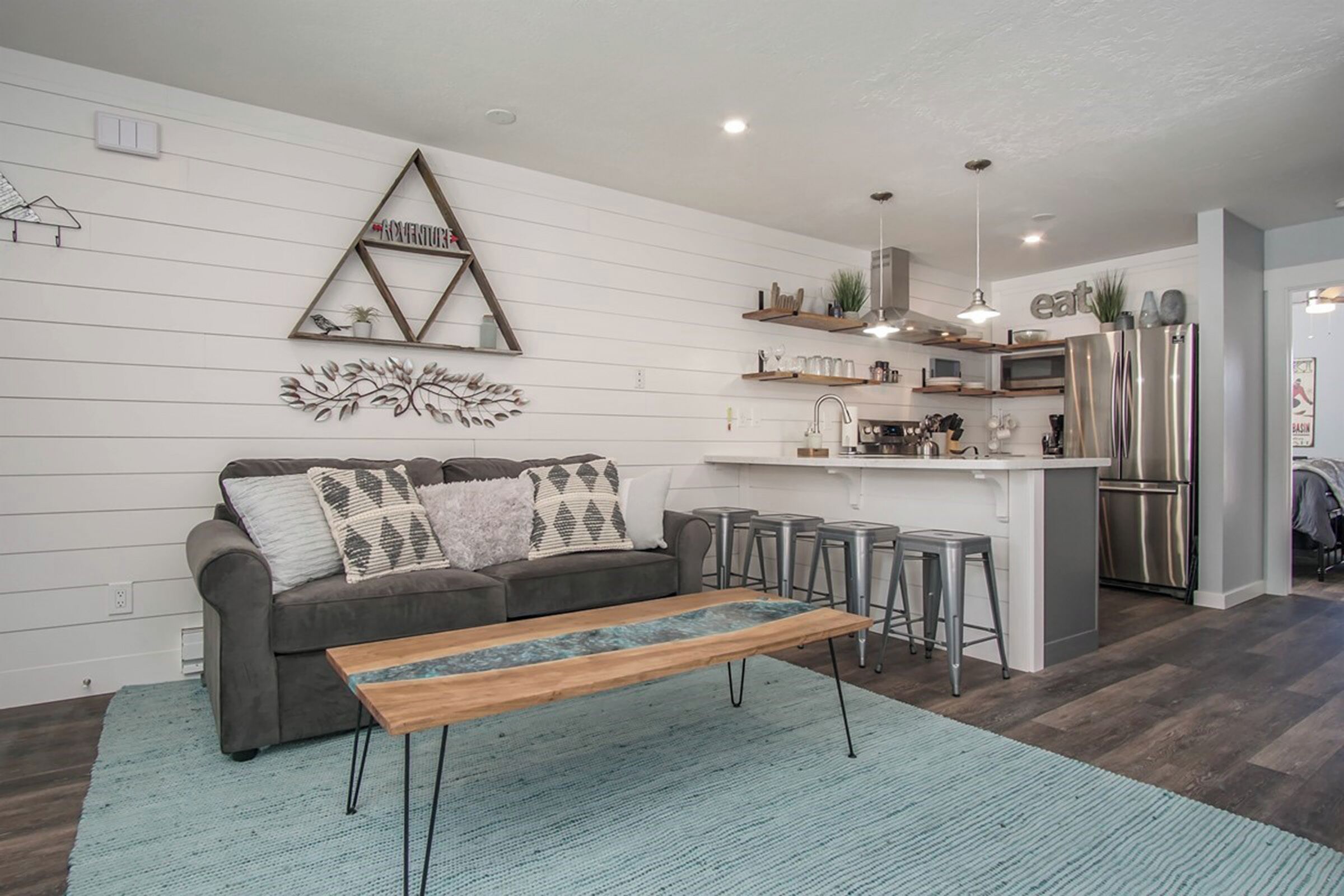 Una cocina moderna con una isla central, taburetes de bar y un refrigerador.