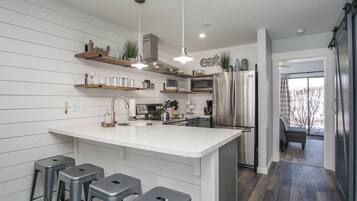 Una cocina moderna con una isla central, electrodomésticos de acero inoxidable y taburetes de bar.