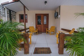 A covered patio area with wooden chairs, a door, and potted plants. - Casa para 8 a 120m da Praia em Porto de Galinhas (Ipojuca)