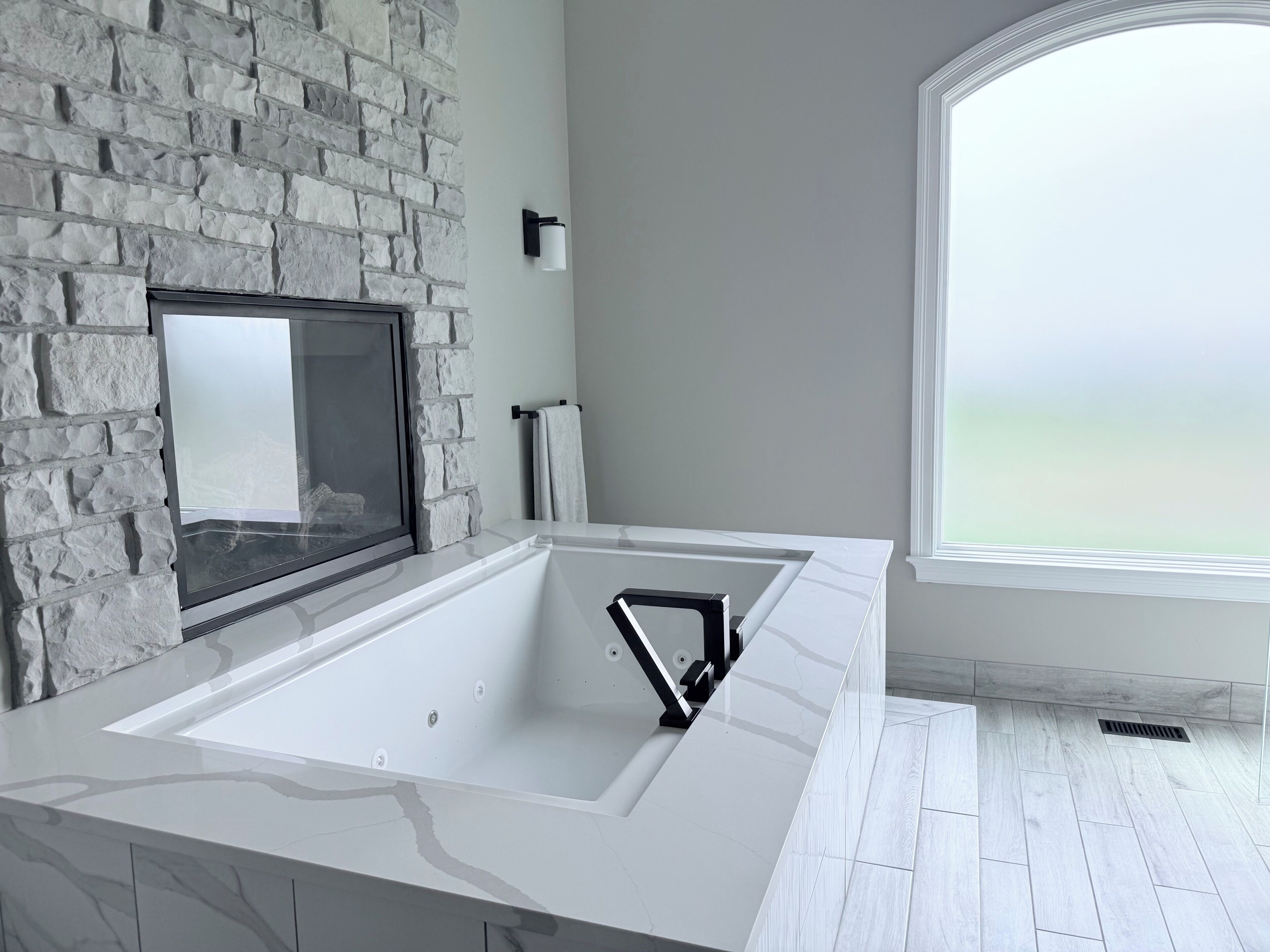 Une salle de bain moderne avec un mur en pierre, une grande fenêtre et un lavabo blanc.