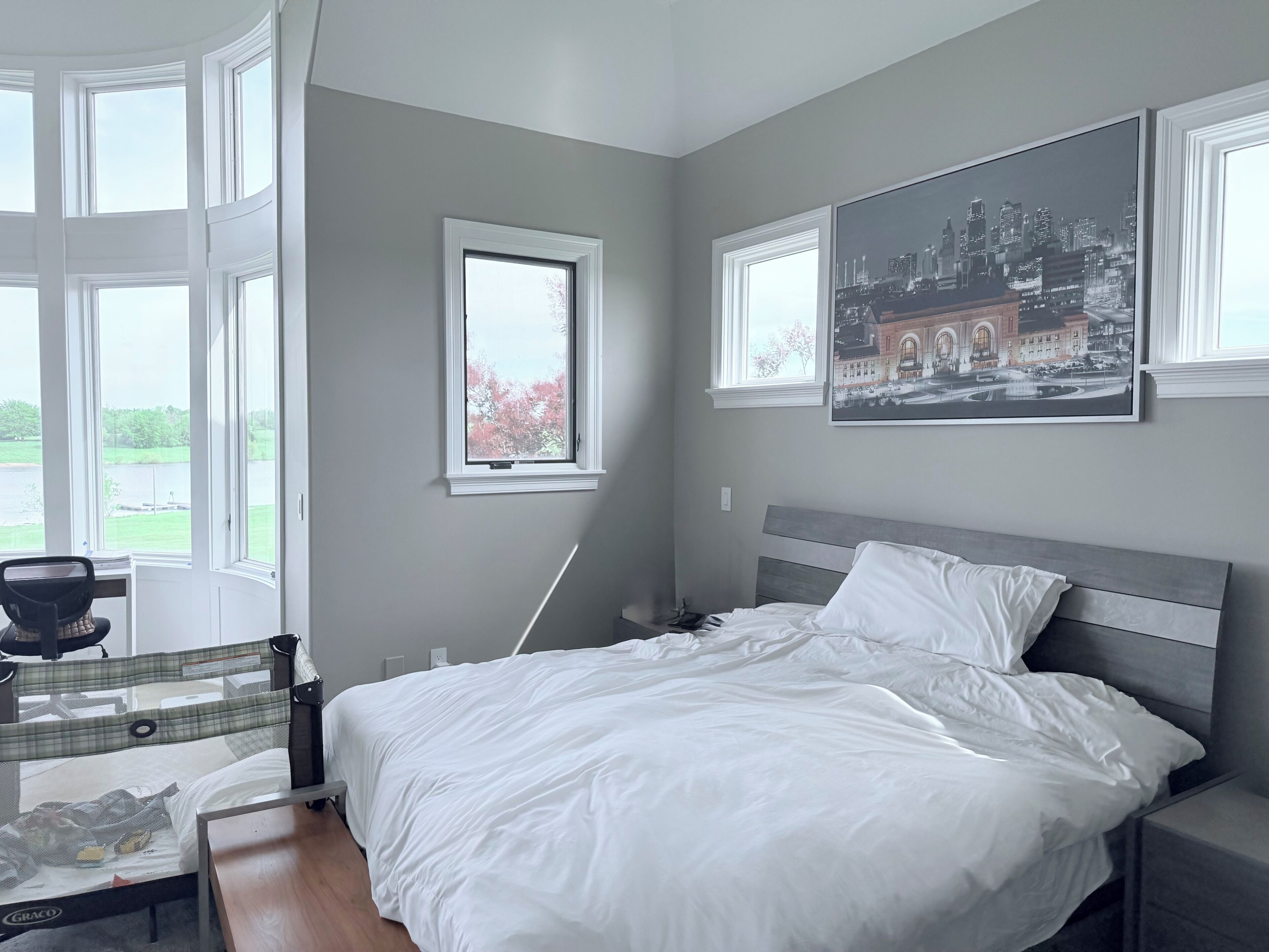 Une chambre à coucher comprenant un lit, un bureau, une chaise, une fenêtre et deux tableaux encadrés accrochés au mur.