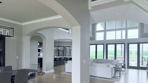 A spacious living area with a dining table, a sofa, and a kitchen in the background.