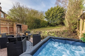 A hot tub with a view of a garden and a brick wall. - Charming 3-bedroom Wolverhampton Home With Private Hot Tub (Wolverhampton)