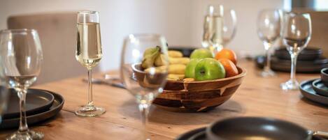 A wooden table with a fruit bowl, wine glasses, and a bowl.