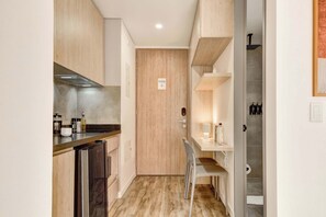 Eine kompakte Küche mit Backofen, Kühlschrank und einer Holztür.