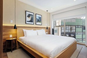 A modern hotel room with a large bed, a small bedside table, a wall-mounted lamp, and framed pictures. - w* | Amazing 2BR w/ Private Terrace in Hipodromo (Ciudad de México)