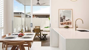 A modern kitchen with a white countertop, a sink, and a ceiling fan. - Sage Palmview - Home Away From Home (Mooloolaba Region)