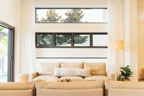 Ein modernes Wohnzimmer mit einer Couch, einem großen Fenster mit Jalousien und einer Stehlampe.