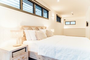 Ein Schlafzimmer mit Bett, Nachttisch, Lampe und einem an der Wand befestigten Fernseher.