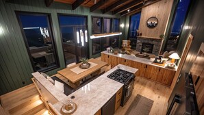 A modern kitchen with wooden cabinets, a built-in stove, and a large window overlooking the city. - Sunshine Ridge View - New Remodel - New Listing! (Anchorage)