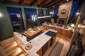 A modern kitchen with wooden cabinets, a built-in stove, and a large window overlooking the city. - Sunshine Ridge View - New Remodel - New Listing! (Anchorage)