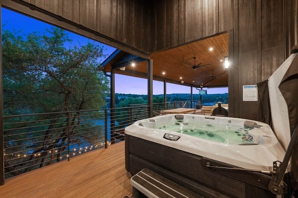 Ein Whirlpool auf einer Holzterrasse mit Blick auf Bäume und eine ferne Landschaft.