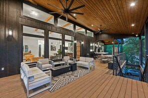 Uma área externa ampla com mobiliário moderno, janelas grandes e um deck de madeira.