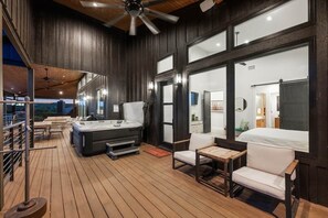 Banheira de hidromassagem, área de estar e grandes janelas em um deck de madeira.