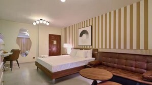 Une chambre d’hôtel avec un lit, un canapé, une table à manger et une chaise.
