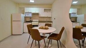 Une cuisine moderne avec des meubles blancs, une cuisinière et un four à micro-ondes. On y trouve une table à manger avec six chaises.